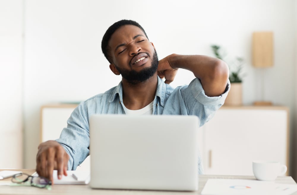 Man with neck pain using laptop