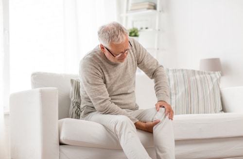 Elderly man holding knee in pain