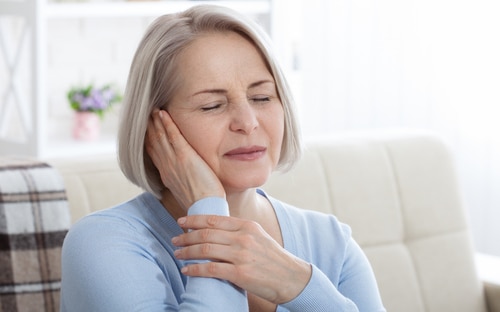 Elderly lady touching face in pain