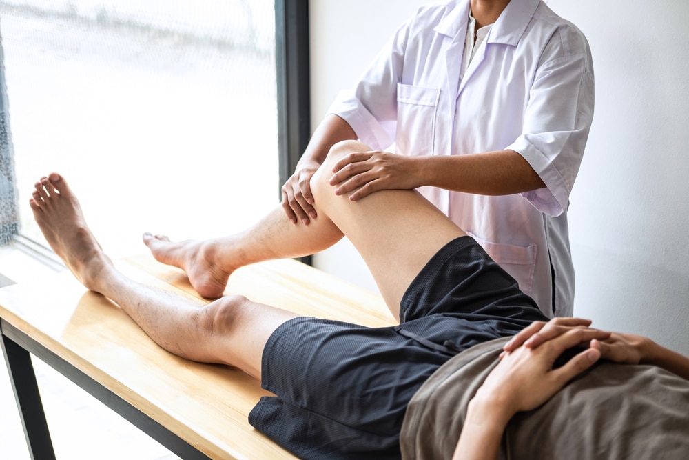 Osteopath treating man with knee pain