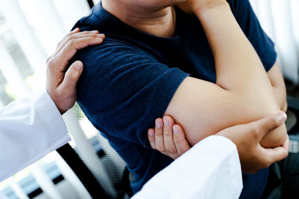 Osteopath examining man's elbow