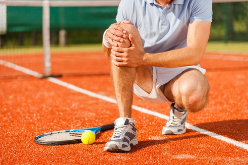 Tennis player holding leg in pain