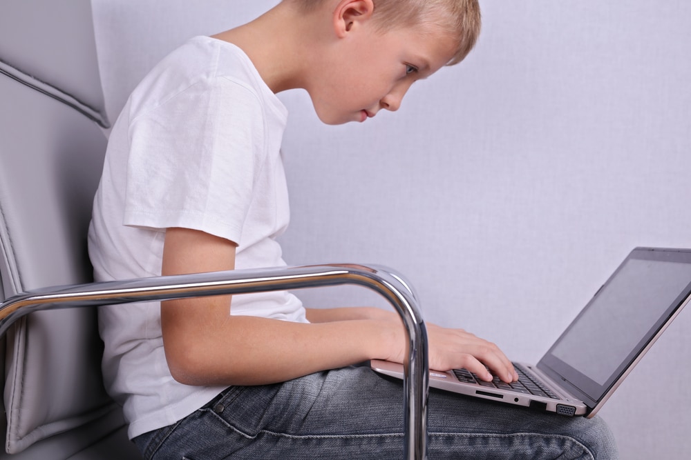 Child using laptop with very poor posture