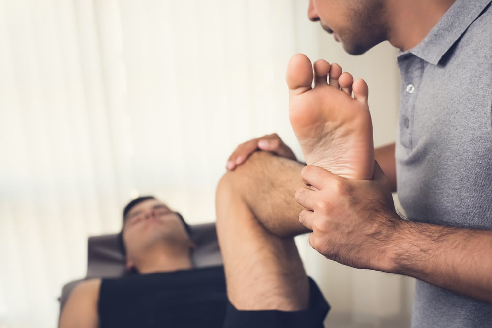 Osteopath treating man with foot pain